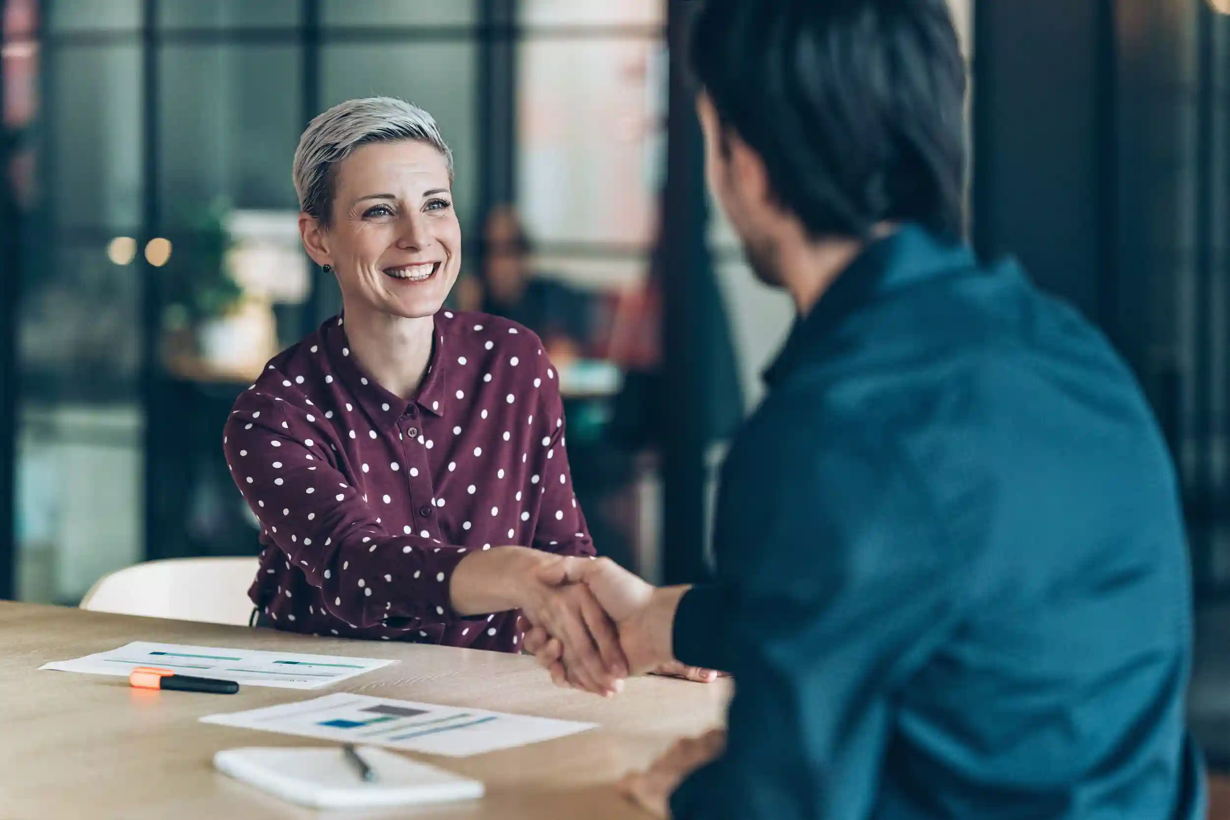 Smiling businesswoman greeting young businessman.