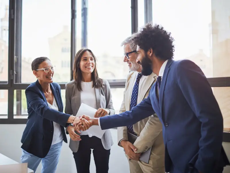 A group of coworkers welcoming one another at a meeting.